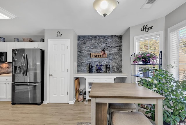 kitchen featuring white cabinetry, stainless steel fridge with ice dispenser, backsplash, and black microwave