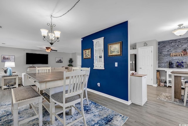 dining area featuring ceiling fan with notable chandelier and light wood-type flooring