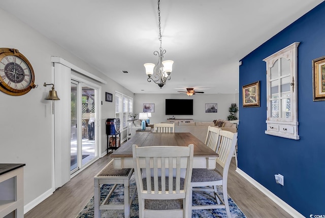 dining room with ceiling fan with notable chandelier and hardwood / wood-style floors