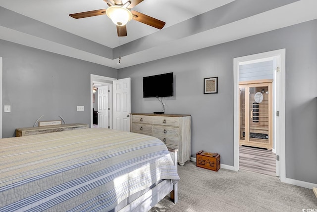 bedroom with light colored carpet, ceiling fan, and a tray ceiling