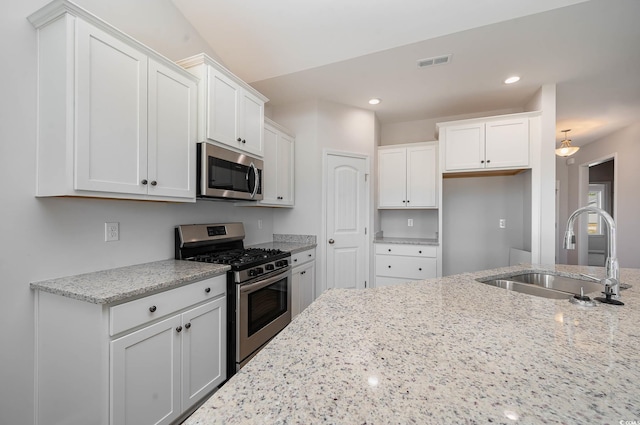 kitchen featuring stainless steel appliances, sink, white cabinets, and light stone counters