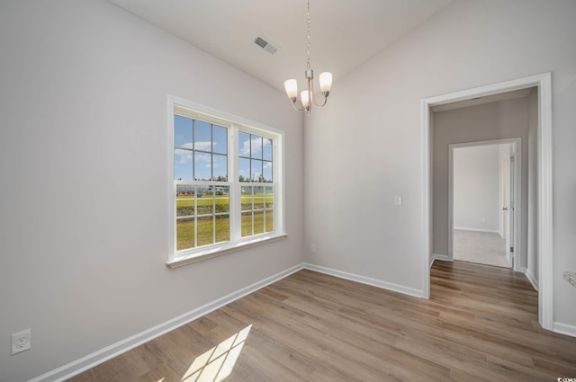 unfurnished dining area featuring lofted ceiling, light hardwood / wood-style flooring, and a chandelier