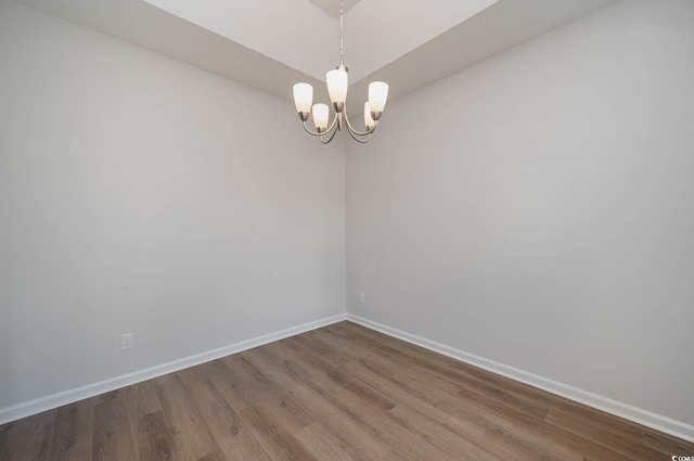 unfurnished room with hardwood / wood-style floors and a notable chandelier