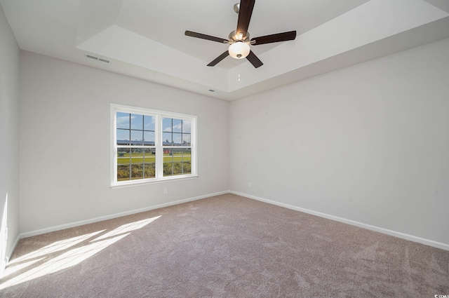 spare room featuring ceiling fan, a raised ceiling, and carpet