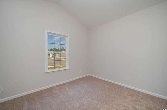 carpeted spare room featuring lofted ceiling