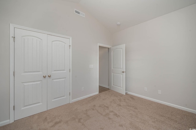 unfurnished bedroom with vaulted ceiling, light colored carpet, and a closet