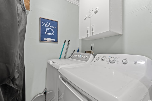 laundry area featuring crown molding, washer and clothes dryer, and cabinets