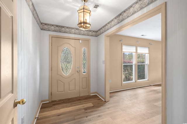 foyer featuring an inviting chandelier, visible vents, light wood-type flooring, and baseboards