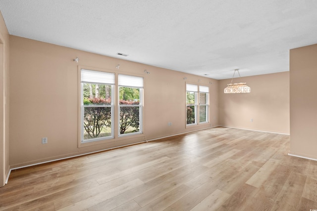 spare room featuring visible vents, light wood-type flooring, and baseboards