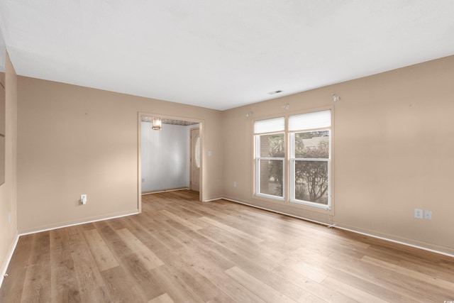 empty room with baseboards, visible vents, and light wood-style floors