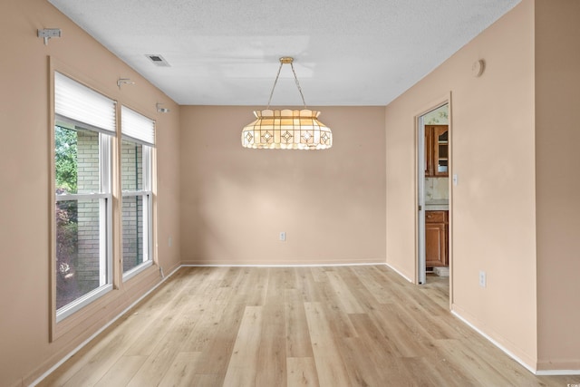 unfurnished dining area with visible vents, light wood finished floors, and baseboards