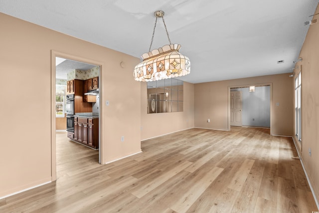 unfurnished dining area featuring baseboards and light wood finished floors
