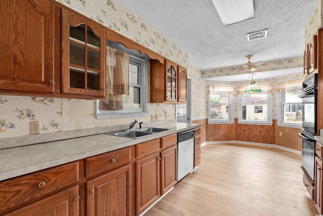 kitchen featuring a sink, light countertops, wallpapered walls, dishwasher, and a ceiling fan