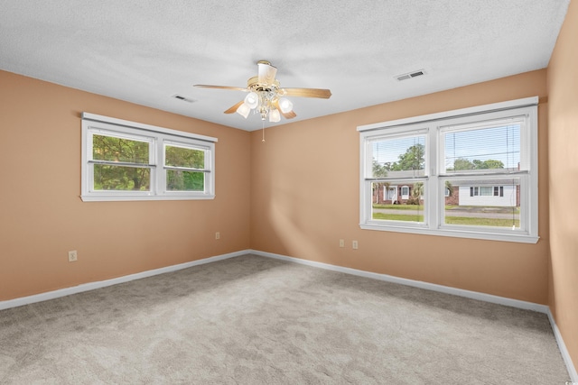 carpeted empty room featuring baseboards, visible vents, and ceiling fan