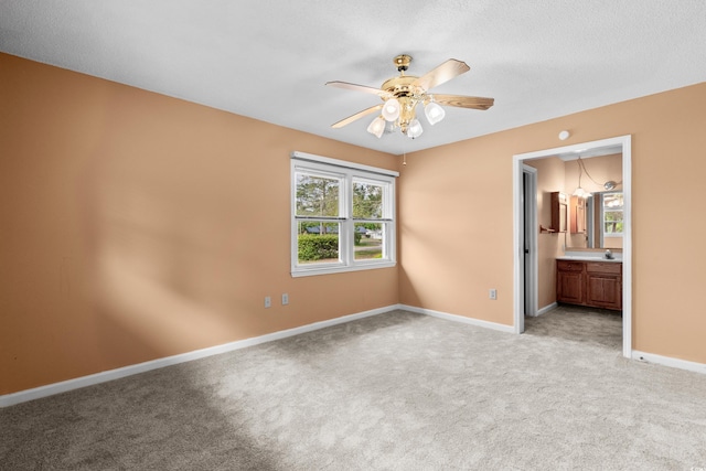 unfurnished bedroom with ensuite bathroom, multiple windows, light colored carpet, and baseboards