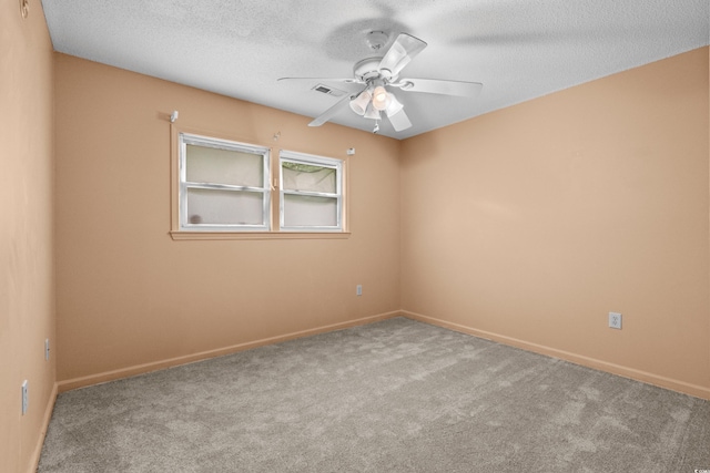 carpeted empty room with a ceiling fan, visible vents, a textured ceiling, and baseboards