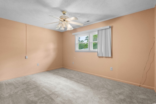 carpeted spare room featuring a textured ceiling, visible vents, ceiling fan, and baseboards