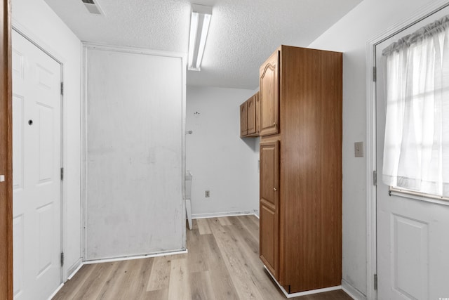 unfurnished room featuring a textured ceiling, visible vents, and light wood-type flooring