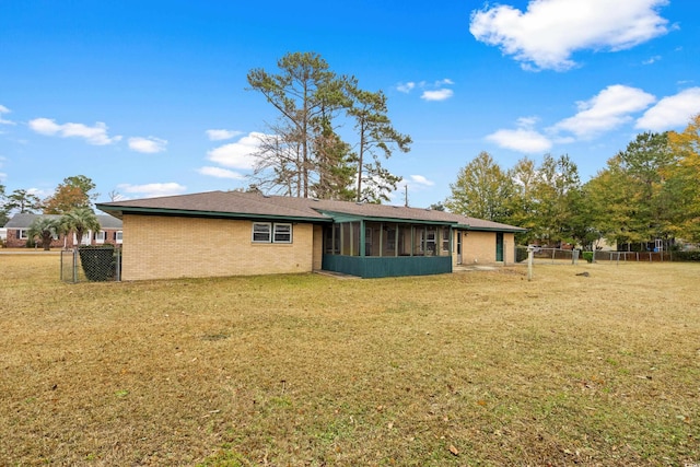 back of house with fence, a lawn, a sunroom, and brick siding