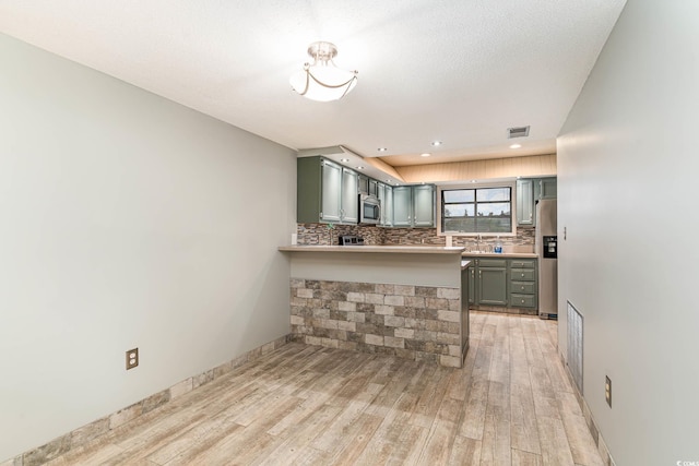 775 Plantation Dr Unit 59, Little River, SC 29566 - kitchen with appliances with stainless steel finishes, backsplash, light wood-style flooring, light countertops, and a peninsula