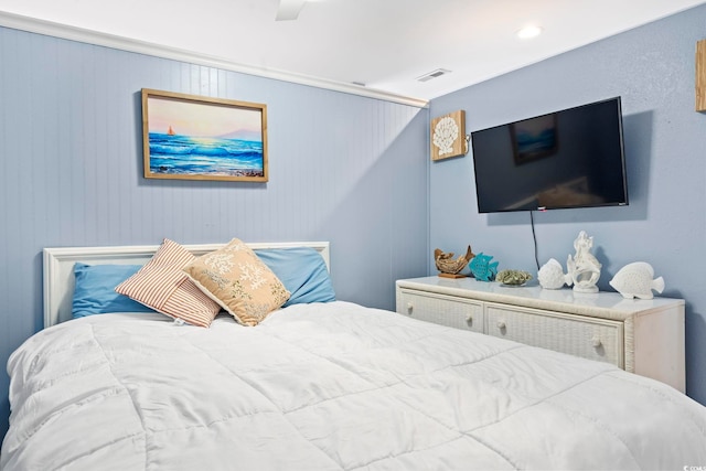 bedroom with ceiling fan and wood walls