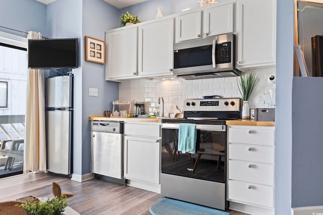 kitchen featuring tasteful backsplash, white cabinetry, stainless steel appliances, and light hardwood / wood-style floors