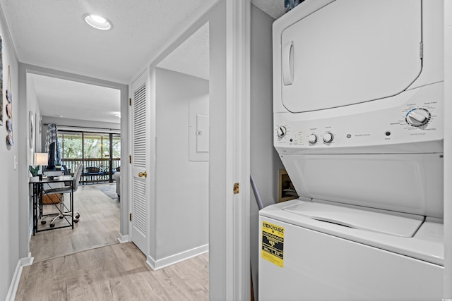 washroom with light hardwood / wood-style flooring, stacked washing maching and dryer, and a textured ceiling