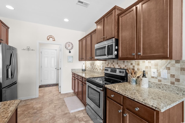 kitchen with stainless steel appliances, light stone counters, and tasteful backsplash