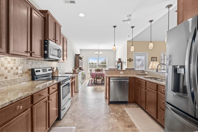 kitchen with pendant lighting, ceiling fan with notable chandelier, sink, light stone counters, and stainless steel appliances