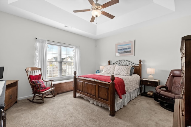 carpeted bedroom with a raised ceiling and ceiling fan