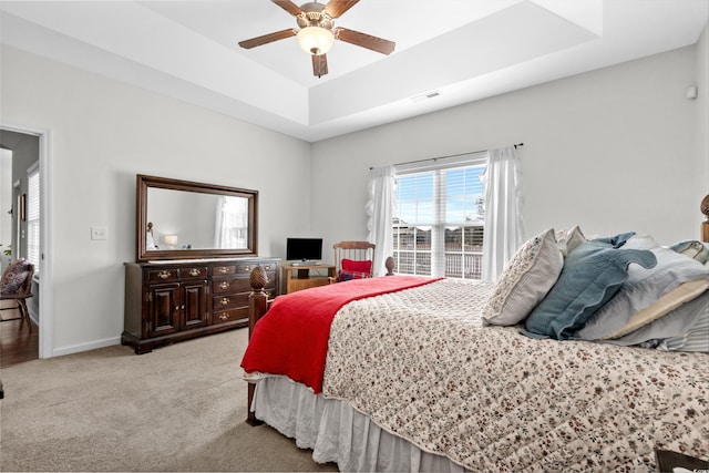 bedroom featuring light colored carpet, ceiling fan, and a tray ceiling