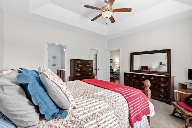 carpeted bedroom featuring ceiling fan and a tray ceiling