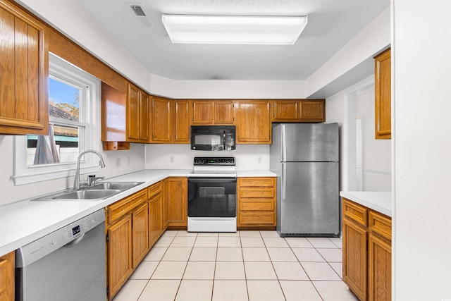 kitchen featuring light tile patterned flooring, a textured ceiling, stainless steel appliances, and sink