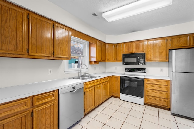 kitchen featuring a textured ceiling, sink, light tile patterned floors, and stainless steel appliances