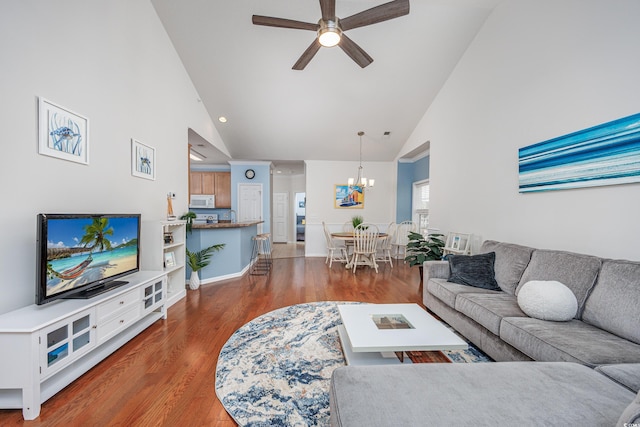 living room with ceiling fan with notable chandelier, high vaulted ceiling, and dark hardwood / wood-style floors