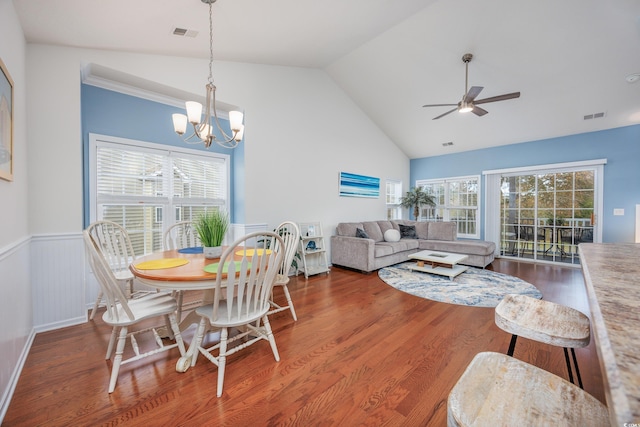 dining space featuring hardwood / wood-style floors, ceiling fan with notable chandelier, and vaulted ceiling