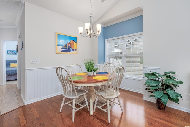 dining room with a chandelier, wood-type flooring, crown molding, and vaulted ceiling