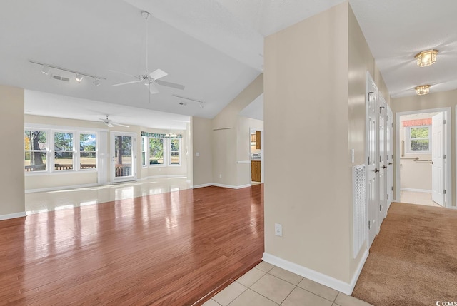 unfurnished living room featuring a healthy amount of sunlight, light hardwood / wood-style floors, ceiling fan, and lofted ceiling