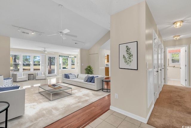 living room with ceiling fan, light hardwood / wood-style flooring, rail lighting, and vaulted ceiling