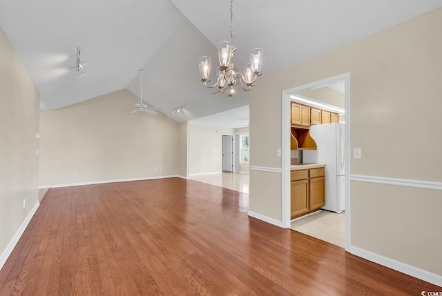 interior space with ceiling fan with notable chandelier, light hardwood / wood-style floors, rail lighting, and vaulted ceiling