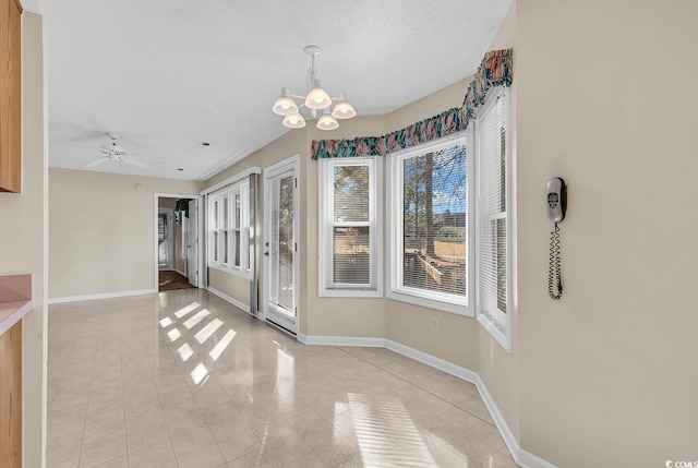 unfurnished dining area with a textured ceiling, light tile patterned floors, and ceiling fan with notable chandelier