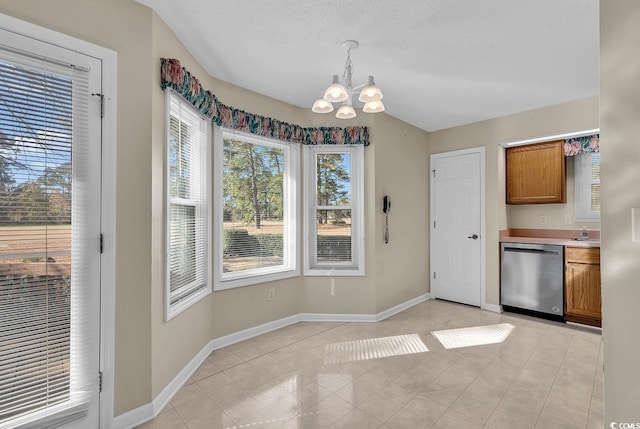 unfurnished dining area featuring sink, light tile patterned floors, a textured ceiling, and a chandelier