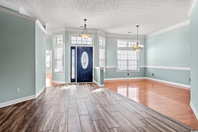 entryway with a textured ceiling, ornamental molding, and a notable chandelier