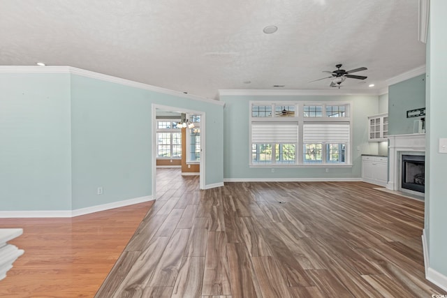 unfurnished living room featuring a textured ceiling, crown molding, ceiling fan with notable chandelier, and hardwood / wood-style floors