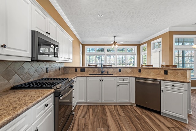 kitchen featuring ceiling fan, kitchen peninsula, sink, white cabinetry, and appliances with stainless steel finishes