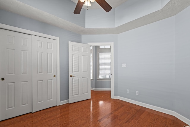 unfurnished bedroom with ceiling fan, a closet, and hardwood / wood-style floors