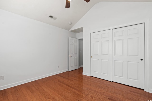 unfurnished bedroom featuring ceiling fan, vaulted ceiling, a closet, and hardwood / wood-style flooring