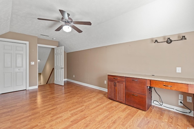 unfurnished office with ceiling fan, light hardwood / wood-style floors, a textured ceiling, and lofted ceiling