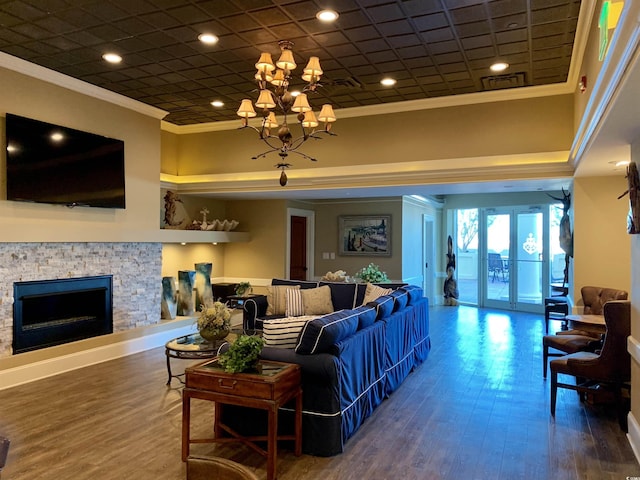 living room with french doors, hardwood / wood-style floors, a chandelier, a fireplace, and ornamental molding