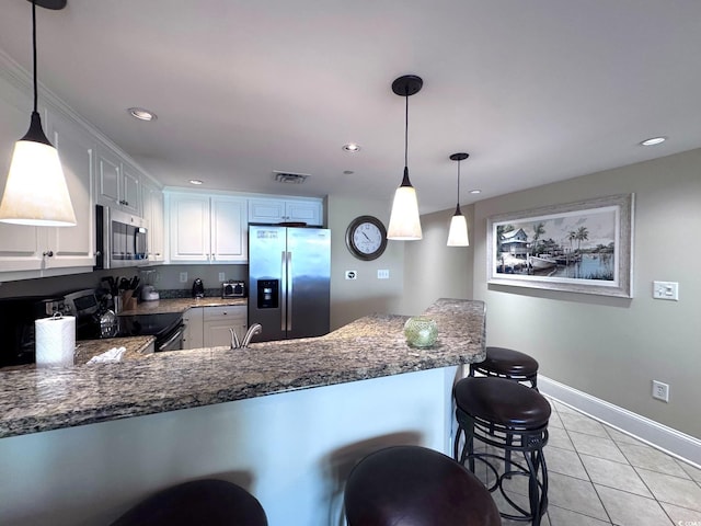 kitchen with stainless steel appliances, kitchen peninsula, pendant lighting, a breakfast bar, and white cabinets